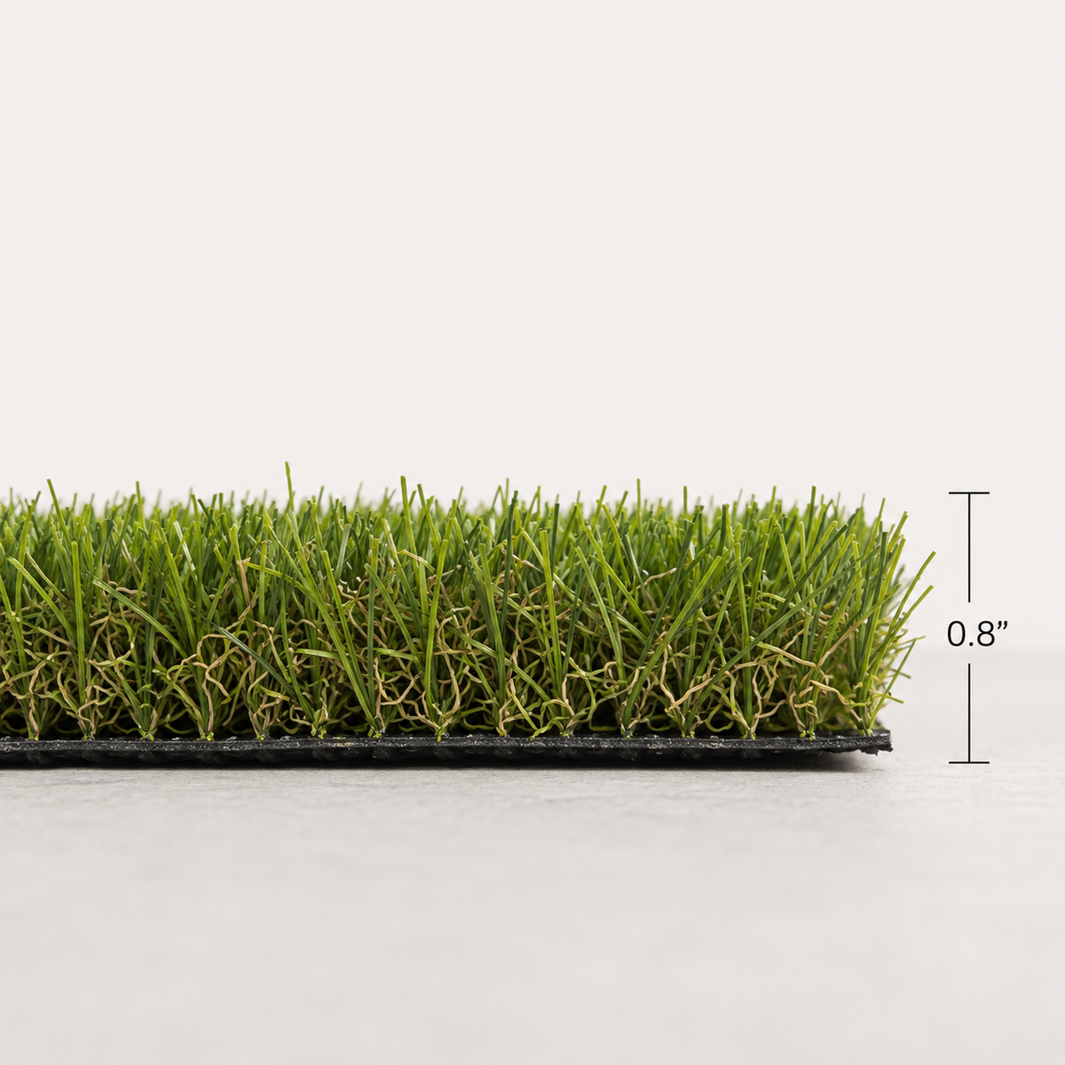 A strip of green artificial turf grass on a black base, shown against a light gray background with a vertical height marker indicating 0.8 inches.   tan thatch.