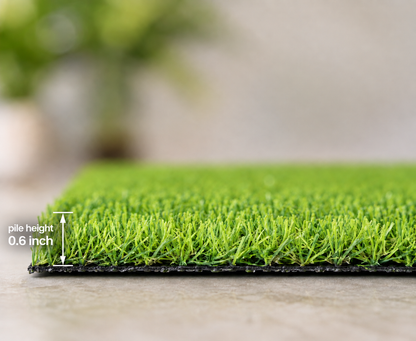 Close-up of a green artificial turf mat with black backing, showing blade texture and a small pile height measurement label reading 0.6 inch.